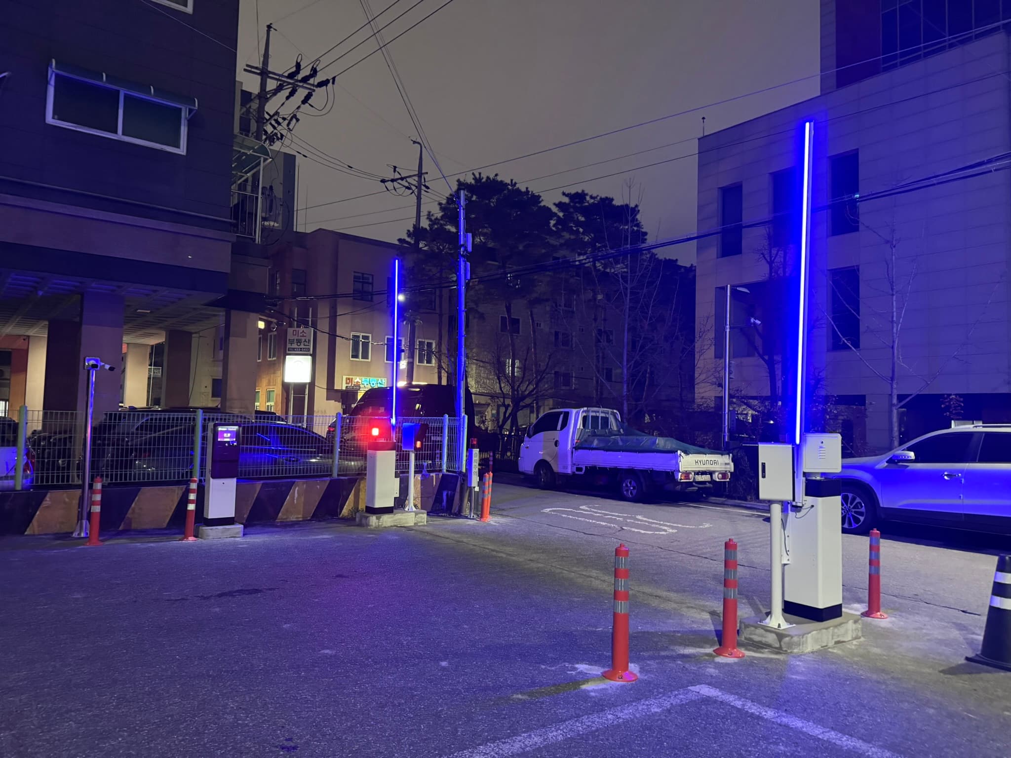주차장 안쪽에서 바라본 출구. 측면의 정산기·보조 LPR과 경계부 차단기의 위치, 출구 맞은편 도로의 주차 차량을 함께 볼 수 있습니다. 출차 시 회전 여유와 반복 전후진을 고려해야 하는 구조입니다.
